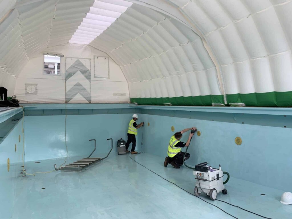 Operatives preparing the drained pool surface inside the Njordair work tent