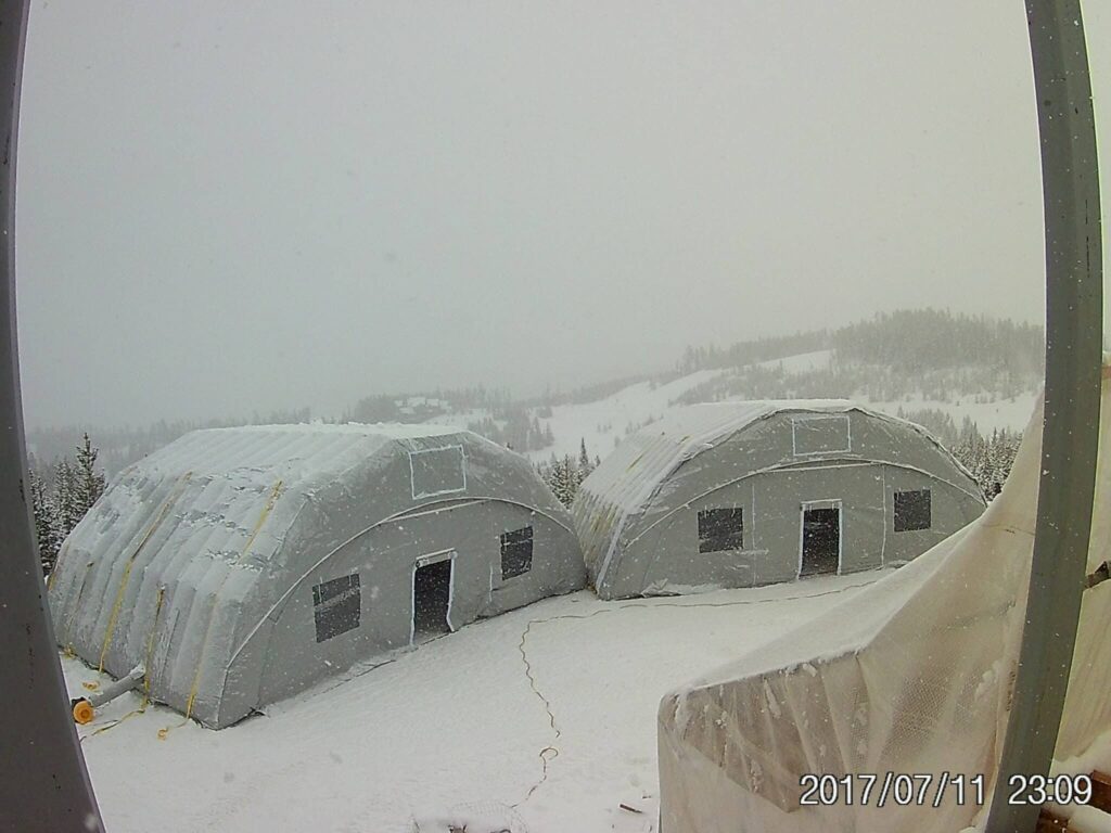 Two Njordair inflatable storage tents in heavy snowfall on a Montana mountainside construction site