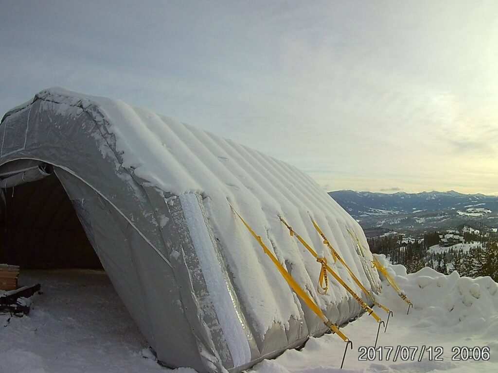 Snow-covered Njordair Constant Air tent anchored on the mountain construction site