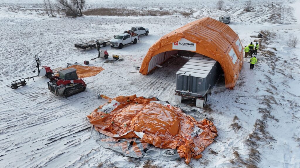 Aerial view of Njordair modules being positioned over the trailer-mounted frac tank in snow